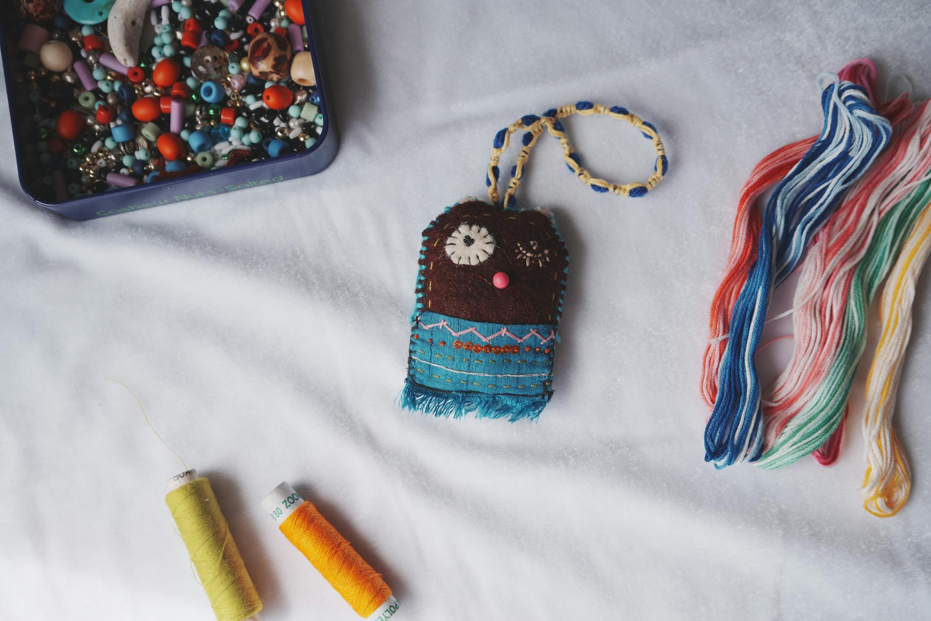 Kolorowe koraliki, nici i mała ręcznie wykonana ozdoba na biurku