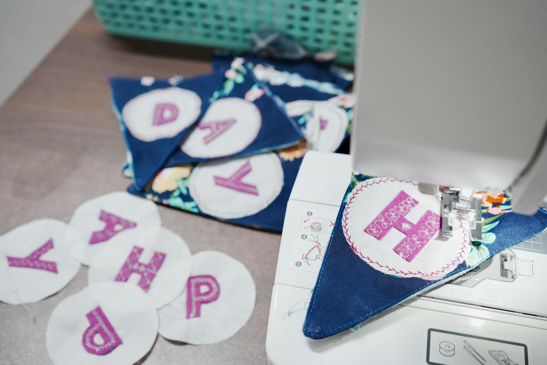 Maszyna szyje kolorowe chorągiewki z literami z resztek materiałów