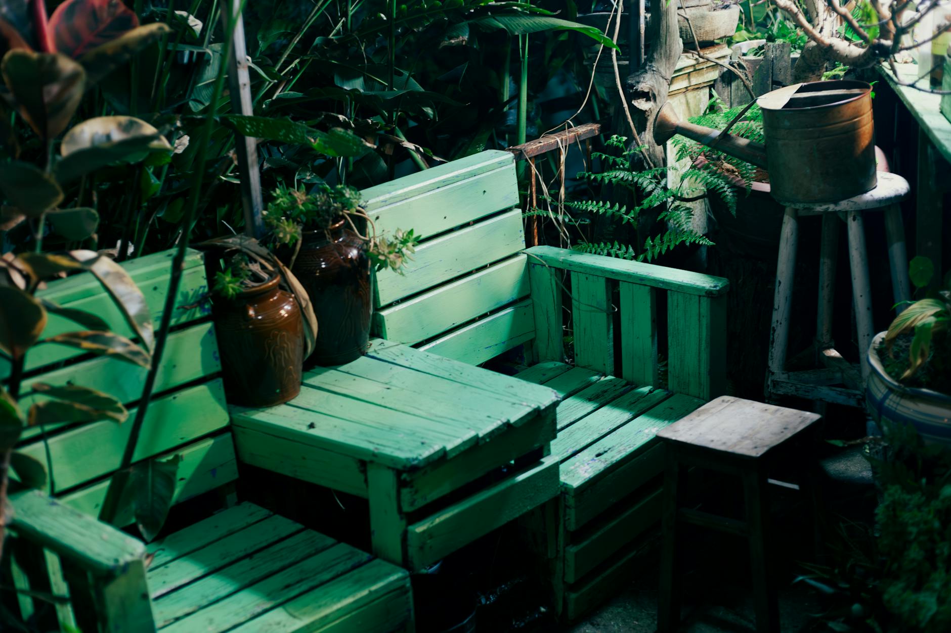 Zielona paletowa ławka ogrodowa z metalową konewką obok