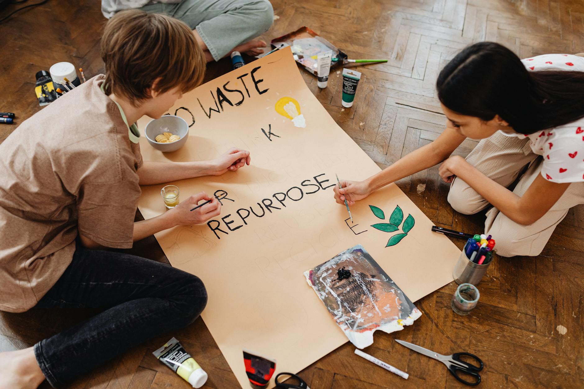 Nastolatki malujące plakat o recyklingu i ponownym wykorzystaniu rzeczy