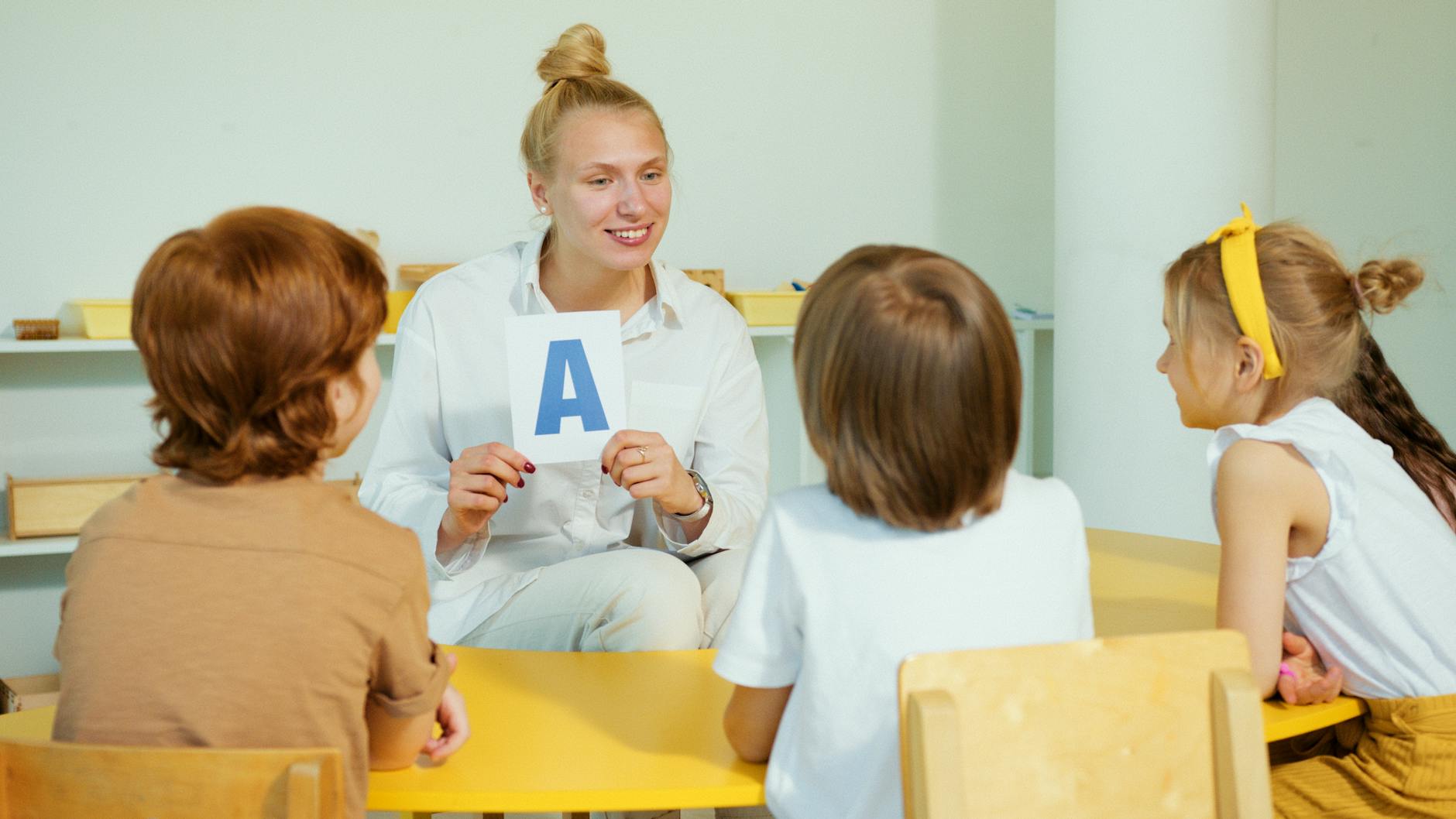 Nauczycielka pokazuje kartonik z literą grupie dzieci w klasie